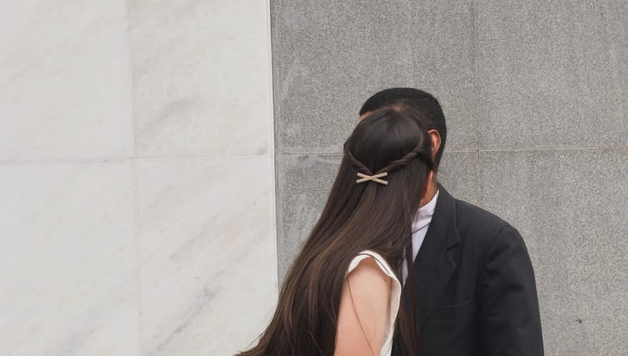 Aline e Arthur se abraçando diante de uma parede de mármore e granito